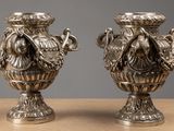 two silver vases that are sitting on a table