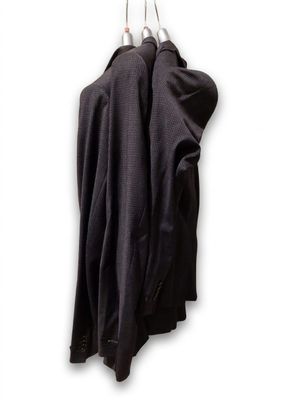 un manteau noir accroché à un crochet sur un mur blanc