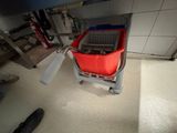 a red bucket sitting on top of a gray cart
