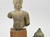 two statues of buddhas and a buddha head on a wooden stand