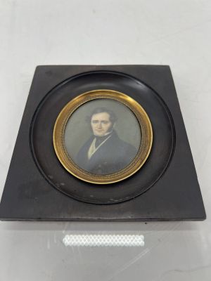an old picture of a man in a suit and tie in a gold frame