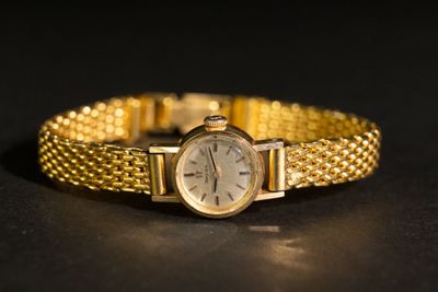gros plan d'une montre-bracelet en or sur une surface noire