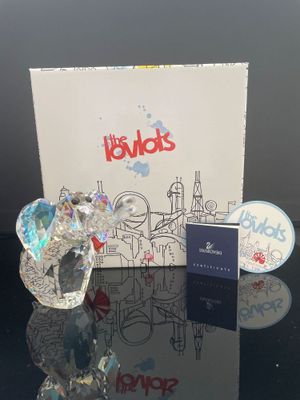 une photo d'une figurine d'éléphant en verre posée sur une table, à côté d'une boîte