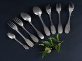 a set of six forks and spoons with leaves on a black surface