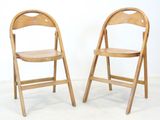 une paire de chaises pliantes en bois adossées à un mur blanc dans une pièce