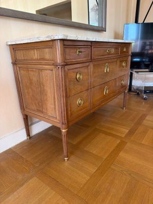 une commode en bois avec un plateau en marbre dans un salon