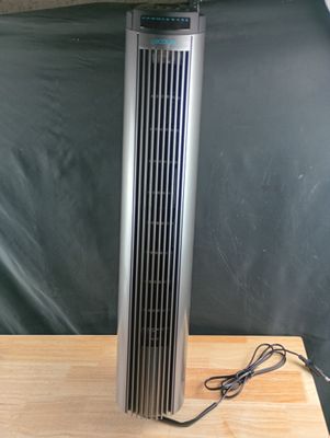 un ventilateur sur pied argenté posé sur une table en bois