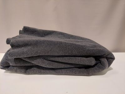 une couverture grise pliée sur une table blanche, sur fond blanc