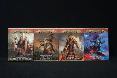 three books of the warhammer series are lined up on a black surface