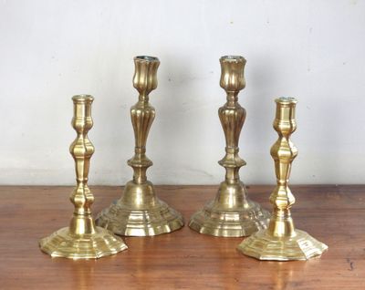 trois bougeoirs en laiton posés sur une table en bois, avec un mur blanc en arrière-plan