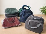 Quatre sacs de couleurs différentes sont posés sur une table en bois.