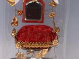 a glass cloche with a red velvet chair under it