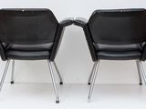 pair of black chairs against a white wall in a white room