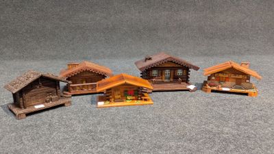 quatre petites maisons en bois sont alignées sur une surface grise