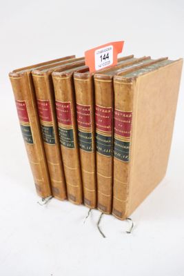 six vieux livres sont empilés sur une surface blanche