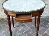 a table with a marble top on a brick floor