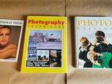trois livres posés sur un lit, avec un appareil photo et un album photo