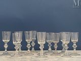 plusieurs verres à vin vides alignés sur une table, avec un mur bleu en arrière-plan