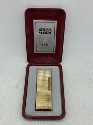 une image représentant un briquet doré dans un étui rouge, posé sur une surface blanche