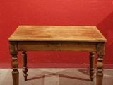 a small table with a wooden top in front of a red wall