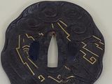 a black tsuba with a gold design on it