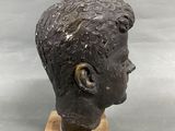 an image of a sculpture of a boy ' s head on a wooden base