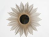 a close up of a sunburst mirror on a white wall
