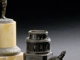 une statue représentant un homme debout sur un socle, à côté d'une lampe