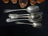 five silver spoons and two silver spoons on a table