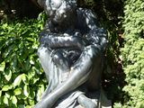 une statue représentant une femme assise sur un rocher dans un jardin