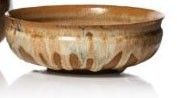 a wooden bowl sitting on a white surface next to a vase