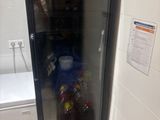 a refrigerator with a glass door in the corner of a room