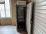 un petit réfrigérateur dans une pièce, avec une chaise à côté