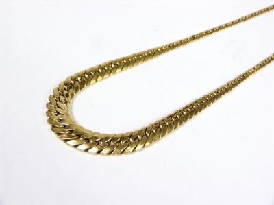 gros plan d'un collier en or sur une surface blanche