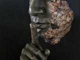 sculpture of a man ' s face on a pedestal with a black background