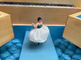 a small figurine of a woman in a dress sitting on a blue surface