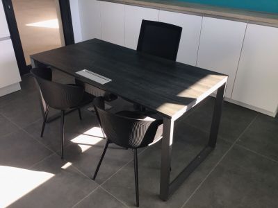 une table noire avec deux chaises et un ordinateur portable posé dessus