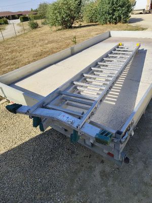 a trailer with a flat bed sitting on top of a gravel field