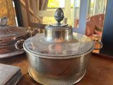 a silver casserole with a lid on a wooden table
