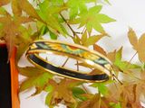 a gold bangle with a black band sitting on top of a box