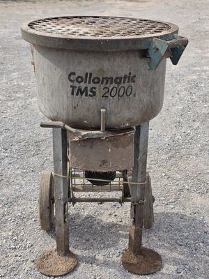 a cement mixer sitting in the middle of a gravel lot