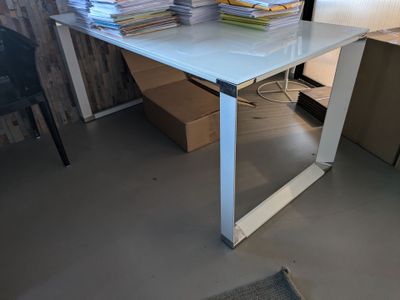 une table en verre sur laquelle est posée une pile de livres