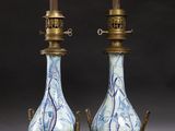 paire de vases bleus et blancs avec des anses en laiton, posés sur des socles