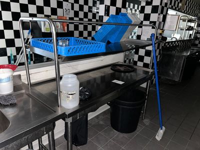 une photo d'une cuisine professionnelle avec un mur à carreaux et des plans de travail en inox