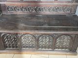 a wooden bench that has been carved and is sitting on a tile floor