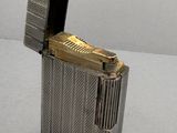 briquet en métal argenté posé sur une table, avec un allumette dans la fente d'allumage