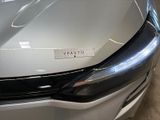 the front end of a silver car with a sticker on it ' s hood