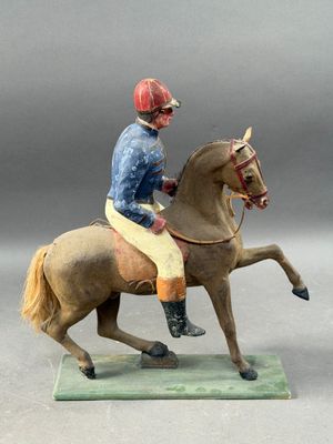 figurine of a man riding a horse on a green base