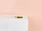 une bague en or sertie d'une pierre noire sur un bloc blanc