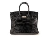 a black crocodile skin handbag on a white background